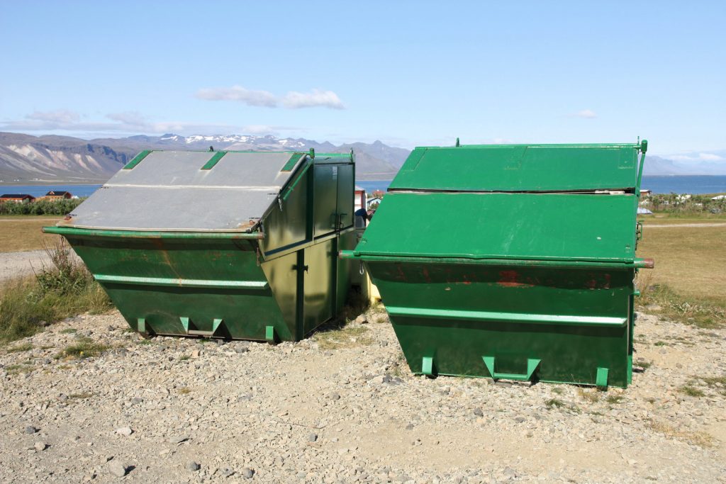 a huge green metal dumpster on the field